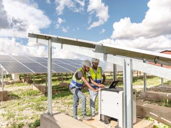 Two technicians work on a solar power plant in Sheder Refugee Camp in Ethiopia.